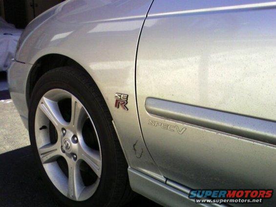 Side view of a silver 2002 Nissan Sentra SE-R Spec V showing the 'SE-R' and 'SPEC V' badges near the rear wheel