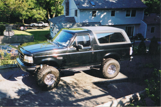 Dark green 1995 Ford Bronco with lifted suspension and off-road tires parked in a driveway