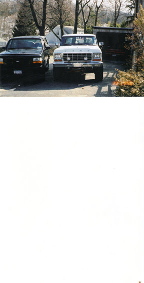 White 1970s Ford F-Series truck parked next to a black Ford Bronco