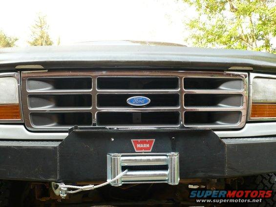 1992 Ford Bronco front grille with chrome bars and Ford logo, above a black bumper with a Warn winch