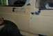 1996 Ford Bronco - A person sands the body of a vehicle, likely a Ford Bronco, as part of repair work.