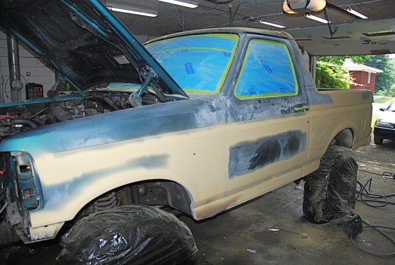 1996 Ford Bronco with hood open, windows taped, undergoing body repair and sanding