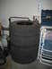 2004 Dodge Durango - Four off-road tires are stacked in a garage next to a propane tank and a toolbox.