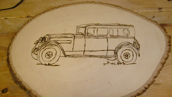 Wood burning art of a classic sedan on a slice of wood