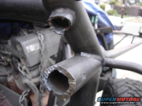 Roll cage tubing with rough cuts, engine block, and chain visible