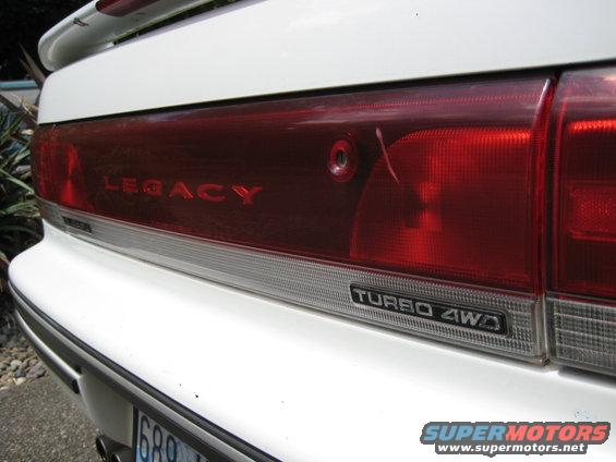 White car's rear bumper and taillight assembly with "LEGACY" and "TURBO 4WD" text