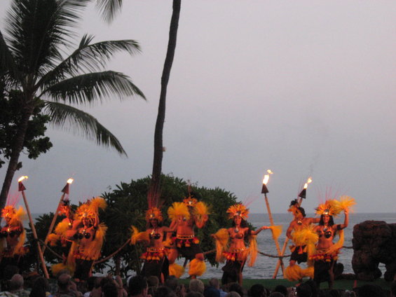 Hula dancers perform with torches at dusk on a beach