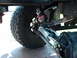 1982 Ford F-100 - Undercarriage view of a vehicle's steering and suspension system, including a hydraulic stabilizer and large off-road tire.
