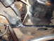 1982 Ford F-100 - Close-up of vehicle undercarriage components, including frame and hoses, with visible rust.