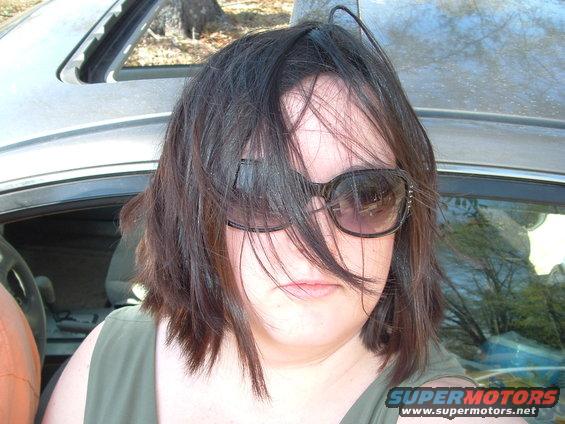 Woman in sunglasses inside a vehicle, with a SuperMotors logo visible