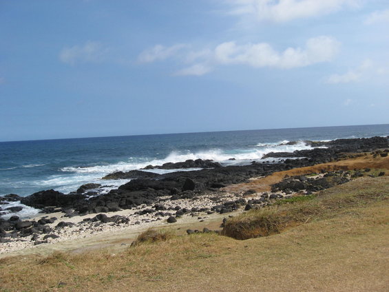 Rocky coastline with waves crashing on shore under a blue sky