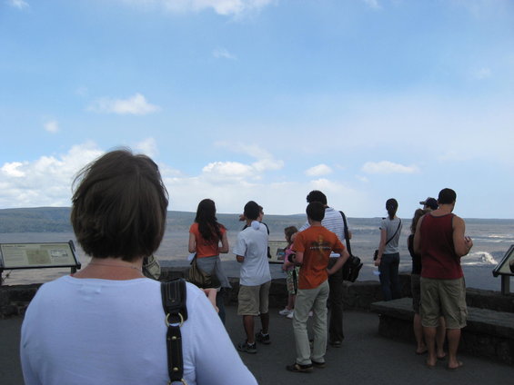 Group of people observing a vast landscape under a cloudy sky