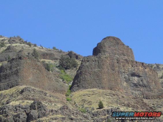Rocky hillsides under a clear blue sky with Supermotors.net watermark