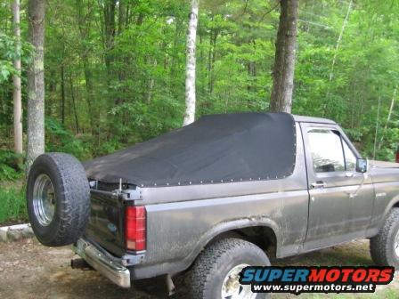 Gray Ford Bronco with a black soft top and a spare tire mounted on the rear