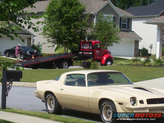 Tan 1979 Chevrolet Camaro parked on street, tow truck behind it