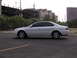 2003 Acura TL - A white sedan is viewed from its side, parked on a paved surface with buildings in the distance.