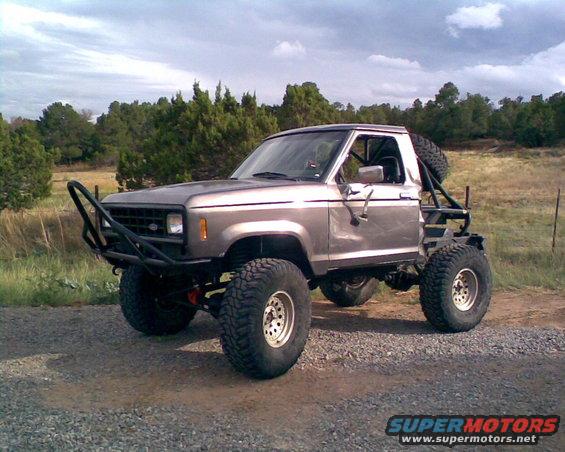 Gray 1983 Ford Bronco II with off-road modifications, including a brush guard and roll cage