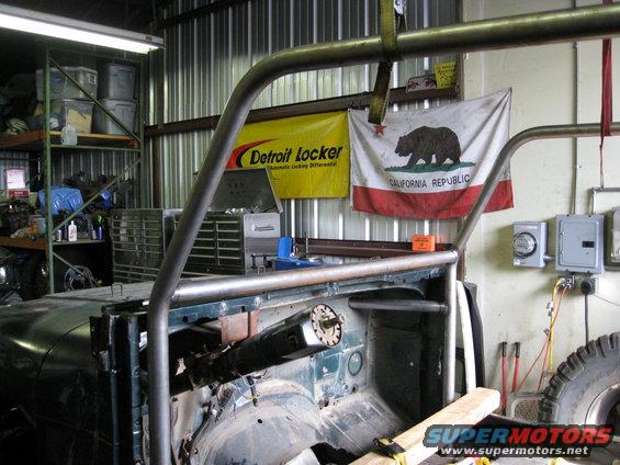 Jeep interior under construction with roll cage, steering column, and California flag