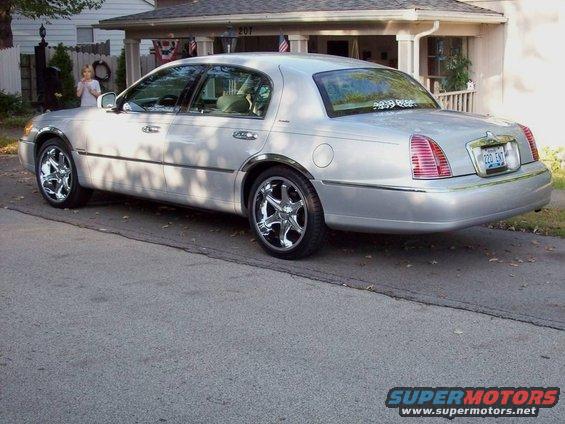 Silver sedan parked in a driveway, chrome wheels, tinted rear window sticker