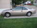 1995 Ford Thunderbird - Side profile of a tan 1995 Ford Thunderbird coupe parked on a concrete driveway.