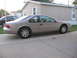 1995 Ford Thunderbird - Side view of a tan Ford Thunderbird parked in front of a beige mobile home.