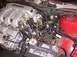 1998 Ford Taurus - Close-up view of engine components, including the manifold and throttle body, with visible wiring and a car battery.