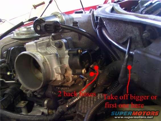 Engine manifold and throttle body with red arrows pointing to hoses
