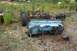1989 Ford Bronco II - A disassembled vehicle, likely a truck or SUV, lies in pieces in an outdoor junkyard setting with overgrown grass.