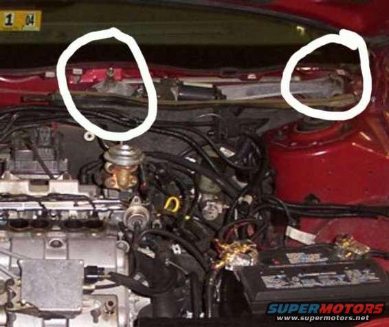 Engine bay showing battery, wiring harnesses, and engine components. Yellow sticker reads '1 04'