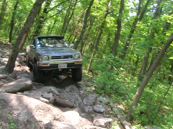 Toyota pickup truck navigating a rocky trail in a forest