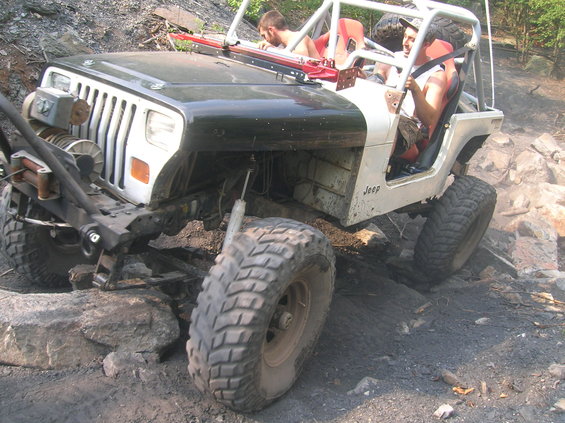 Modified Jeep Wrangler with winch and roll cage on rocky terrain