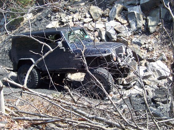 Dark blue Jeep Wrangler Rubicon on rocky terrain, front quarter view