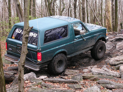 Green 1996 Ford Bronco on rocky trail, "R.I.P. 89-07" on rear window