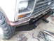 1982 Ford Bronco - Close-up view of the front grille and fender area of a vehicle, showing some wear and tear.