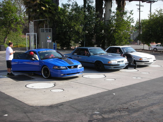 Blue 2000 Ford Mustang with black stripes, driver's door open