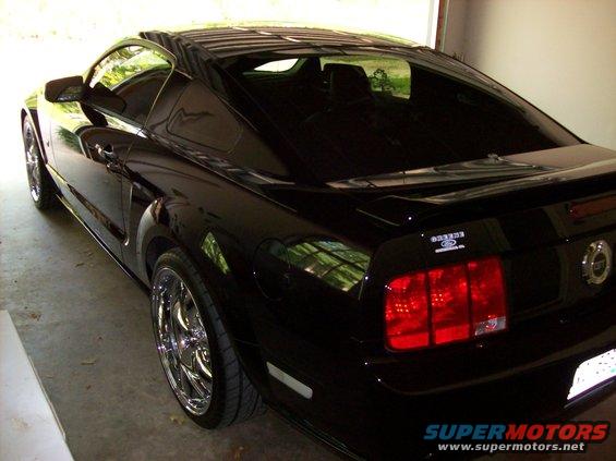 Black Ford Mustang coupe with chrome wheels parked in a garage