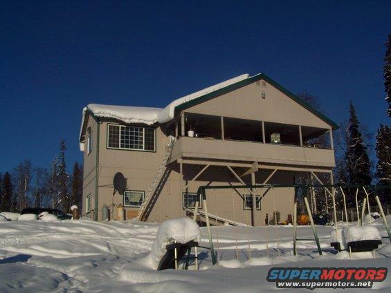 Snow-covered yard with a house and a swing set