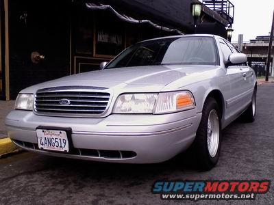 Silver 1998 Ford Crown Victoria parked on street. Front grille and California license plate visible