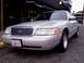 1998 Ford Crown Victoria - A 1998 Ford Crown Victoria is parked on a street in front of a building.