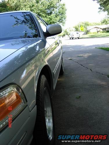 Silver 1998 Ford Crown Victoria, 3/4 front view. Timestamp on headlight