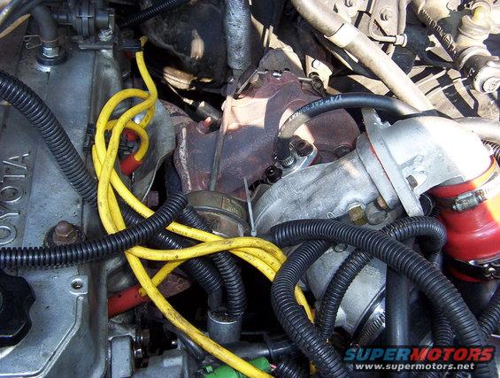 engine bay showing a turbocharger and yellow spark plug wires. 'TOYOTA' is visible on the engine block