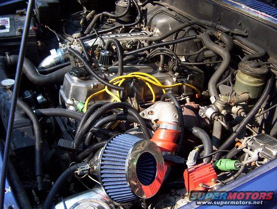 1986 Toyota Hilux engine bay with blue air filter and red ignition module