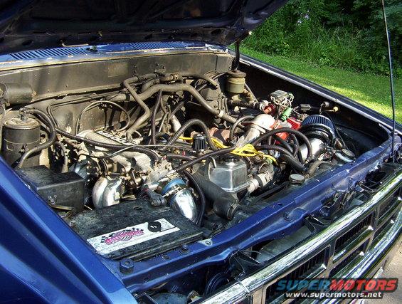 Blue 1986 Toyota Hilux engine bay with aftermarket air filter and chrome grille