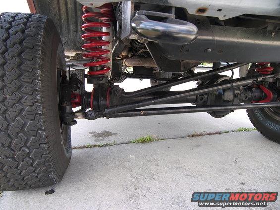 Truck's front suspension with red coil springs and large off-road tire