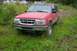 1989 Ford Bronco II - This red Ford Explorer is parked in a grassy area with trees in the background.