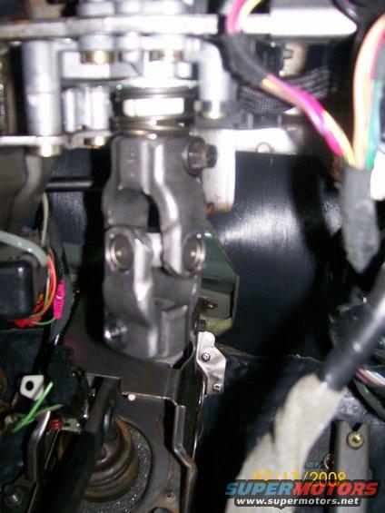 Close-up of a steering column U-joint with wires and metal brackets
