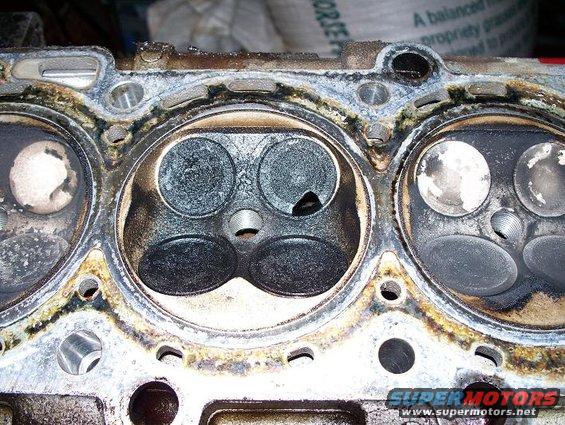 Engine cylinder head with carbon buildup on valves and surrounding metal