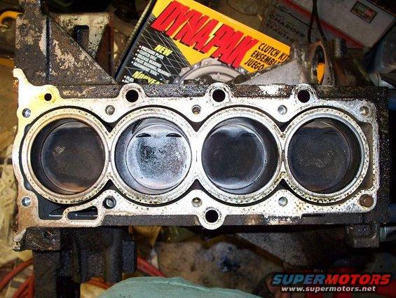 Engine block with four cylinders and pistons visible. A clutch kit box is in the background