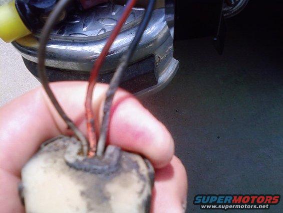 Hand holding a dirty electrical connector with exposed wires