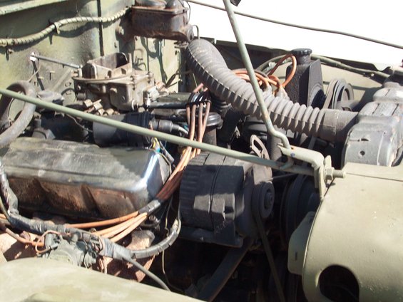 Close-up of a Jeep engine bay showing the carburetor, valve cover, and alternator